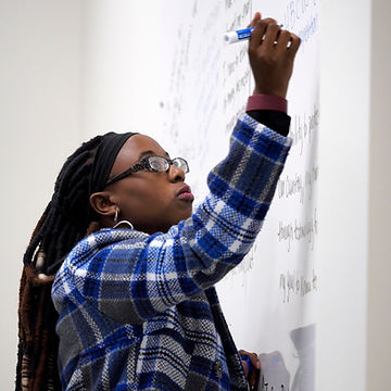 A person writing on a whiteboard
Description automatically generated